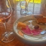Glass of rose wine paired with bread, cheese, chocolate truffle and watermelon radish for garnish on a white plate