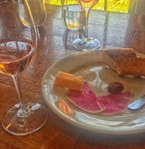 Glass of rose wine paired with bread, cheese, chocolate truffle and watermelon radish for garnish on a white plate